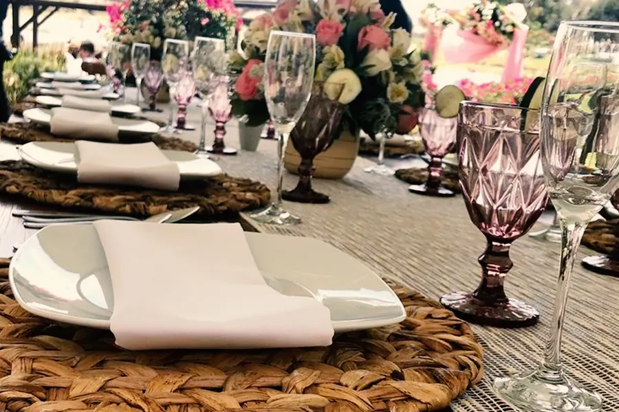 comida-de-chef-a-domicilio-con-mobiliario-montaje-elegante-con-cristaleria-rosa-y-decoracion-floral